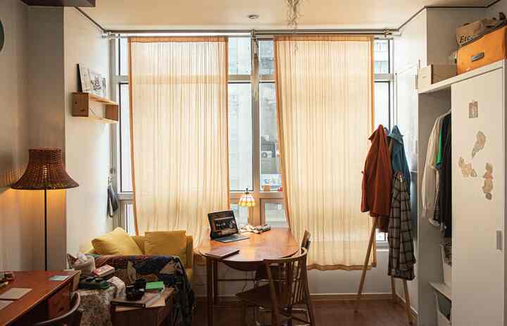 ブラウンの木目調とアイボリーのカーテンが調和する二人暮らし向けのリビング、自然な照明と落ち着いた作業スペースが配置されたインテリア