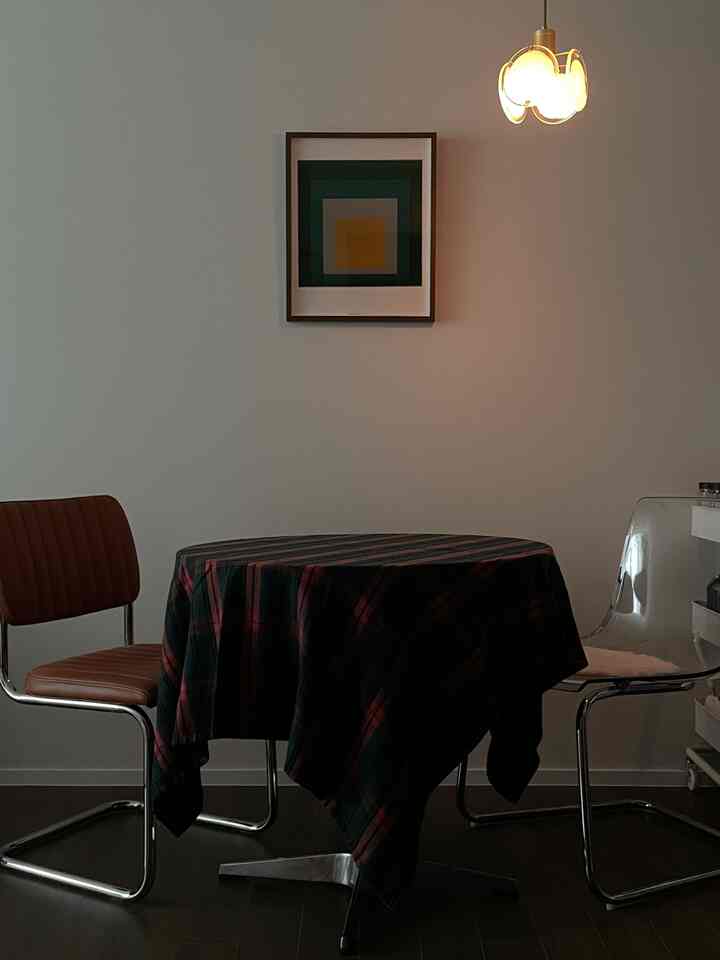 茶色と黒の色調のダイニングルーム、中央にチェック柄のテーブルクロスをかけた丸テーブルと2つの椅子が配置された雰囲気のある空間