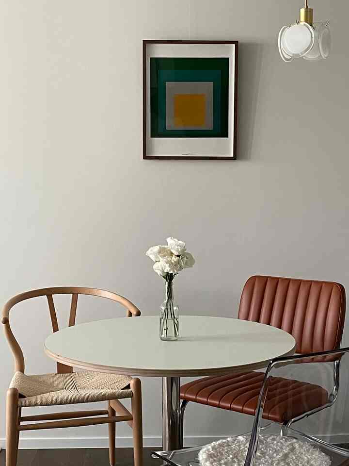 白と木目調のダイニングルーム、丸いダイニングテーブルと様々な椅子が配置されたシンプルでモダンな印象的な空間