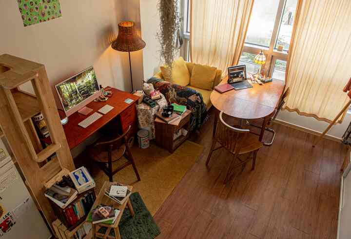 黄色いカーテンのあるリビング、木目調の家具とキャットタワーが配置されたソファとデスクのある雰囲気の良い空間