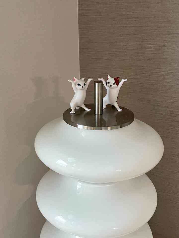 ホワイトとブラウンのトーンでまとめられたモダンな空間、中央に白いランプと猫の置物が配置されたシンプルな雰囲気のインテリア