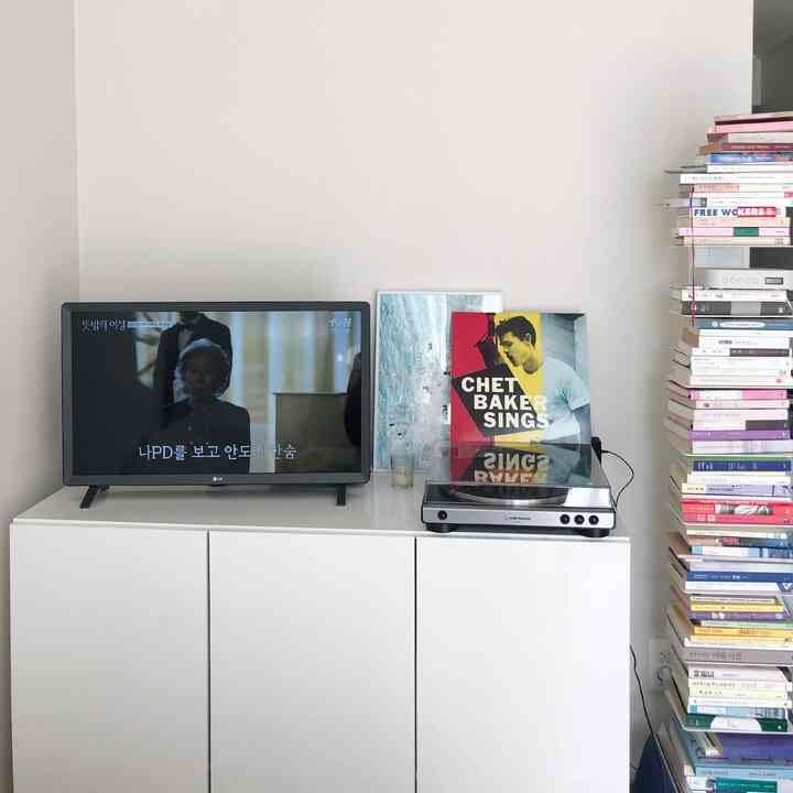 ホワイトとシルバー調のリビング、テレビとターンテーブルが設置された収納キャビネットが印象的なインテリア