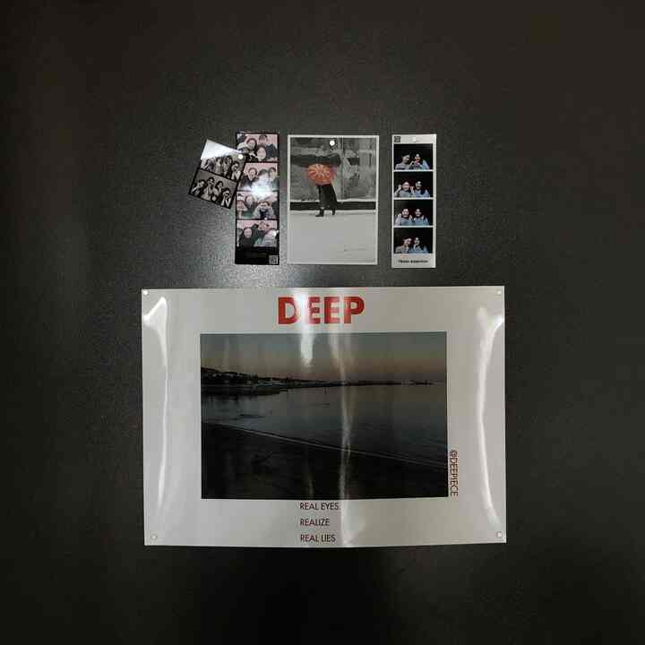 暗いトーンの玄関の壁に大きなDEEPポスターと複数のインスタント写真が配置された雰囲気ある空間