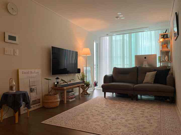 ナチュラルトーンのリビングルーム。茶色のソファとパソコンデスク、ベランダ拡張空間が調和した居心地の良いホームオフィスです。