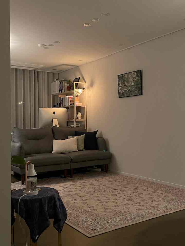 グレーとブラウンのトーンのリビング、グレーのソファ、ペルシャ絨毯、ホームオフィス要素が配置された雰囲気のあるインテリア