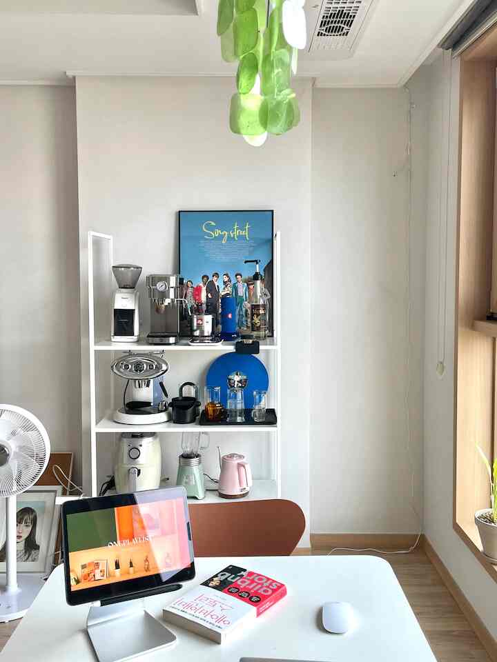 ホワイトトーンのキッチン兼作業スペース、コーヒー器具が並ぶ棚と整ったデスクが配置された落ち着いたおうちカフェの雰囲気