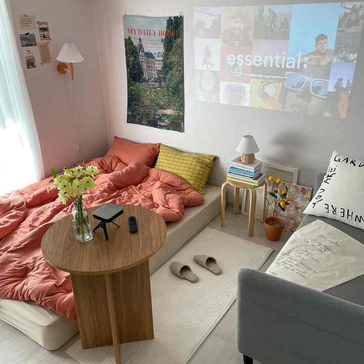 ナチュラルトーンと木製テーブルがある居心地の良い寝室、2人用ソファベッドとプロジェクターが配置された快適な空間