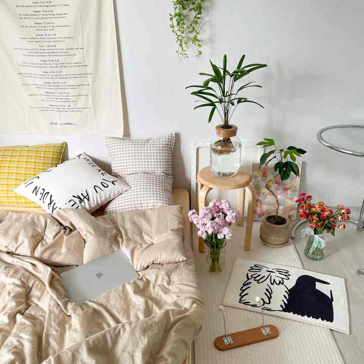 ベージュトーンの寝室、寝具と多様な植物が配置された自然で居心地の良いインテリア