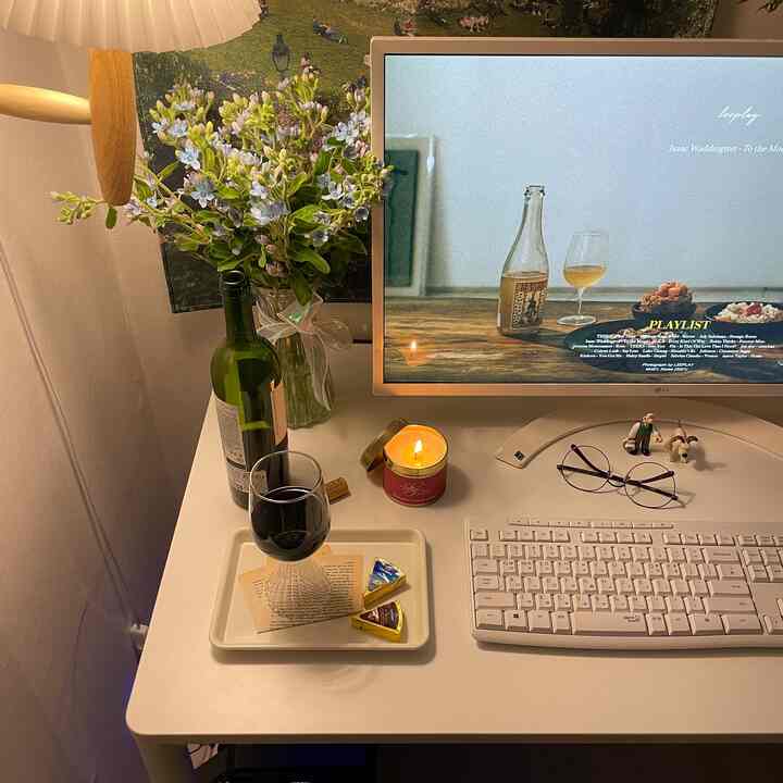 白を基調としたホームオフィス、ワイングラスとキャンドルが置かれたデスクが温かみのある印象的な空間