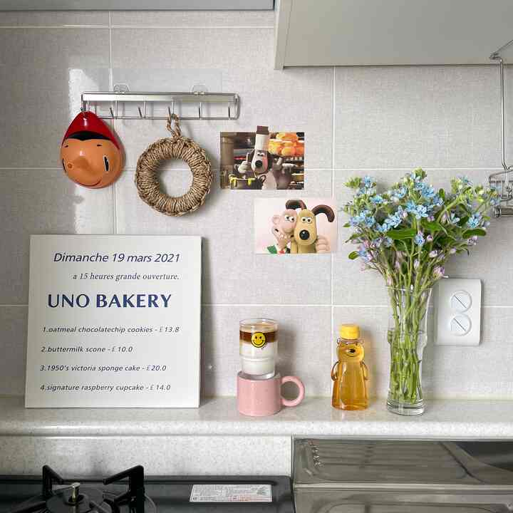 明るくナチュラルな色調のキッチン、壁に飾られた額と花瓶、コーヒーカップが置かれた雰囲気のあるおうちカフェ