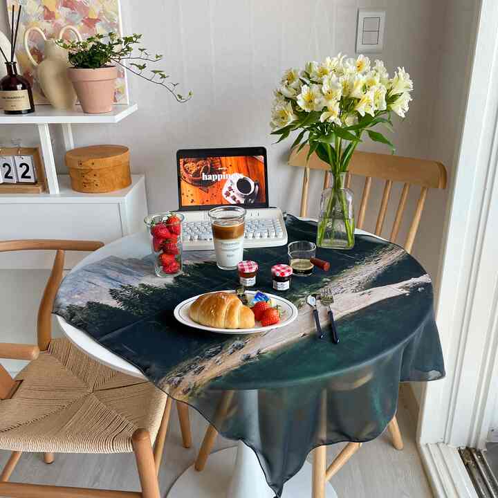 白い壁と木目調の椅子が配置されたキッチンスペース、丸テーブル上におうちカフェの小物と花瓶が置かれた雰囲気のあるインテリア