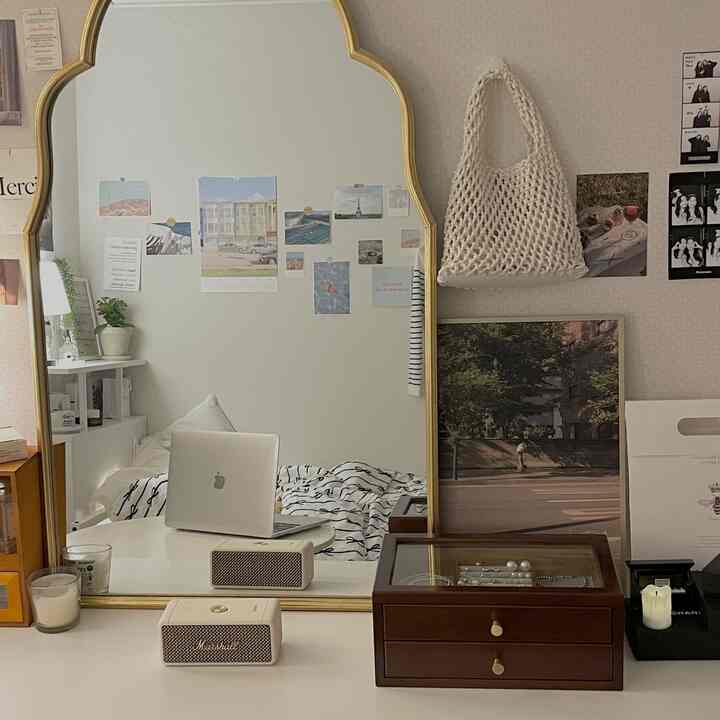 白とゴールドの色調の寝室、デスクにノートパソコンとマーシャルのスピーカー、大きなゴールドフレームの鏡が配置された落ち着いた雰囲気のインテリア