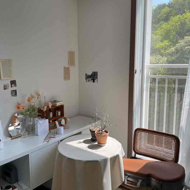 白を基調としたバルコニー横のナチュラルな空間、テーブルと椅子が自然光に照らされている雰囲気のあるインテリア