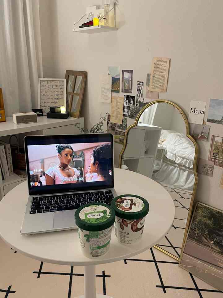 白とベージュのトーンのコンパクトな寝室、ゴールドフレームの鏡と整った丸テーブルが配置されたモダンな空間