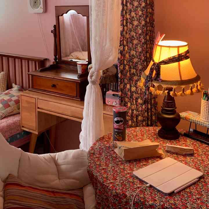 温かみのあるブラウンとレッドのヴィンテージ風の部屋、花柄のテーブルクロスとテーブルランプが印象的な雰囲気のあるインテリア