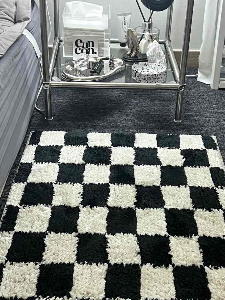 モノトーンとダークグレーのリビング、チェッカーボード柄のカーペットとメタルフレームのサイドテーブルが配置されたシンプルなインテリア