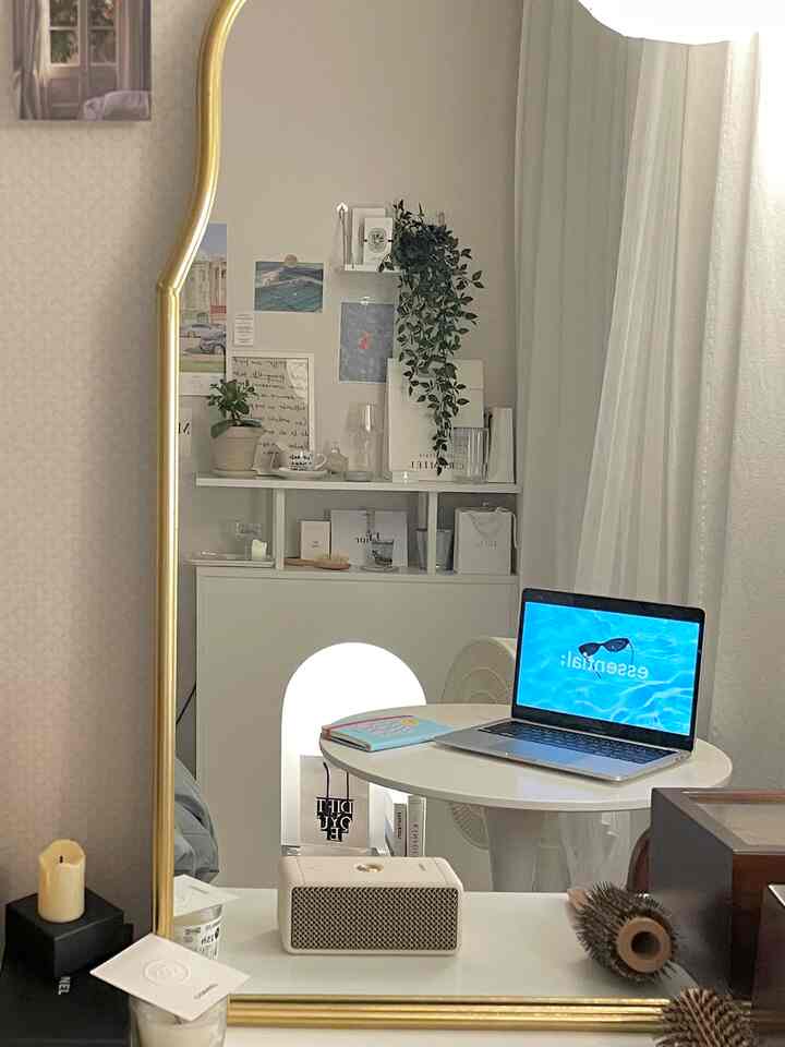 ホワイトとゴールドの調和した一人暮らし用ホームオフィス、金色の縁取りの大きな鏡とアーチ型のコンソールテーブルが洗練された雰囲気を演出