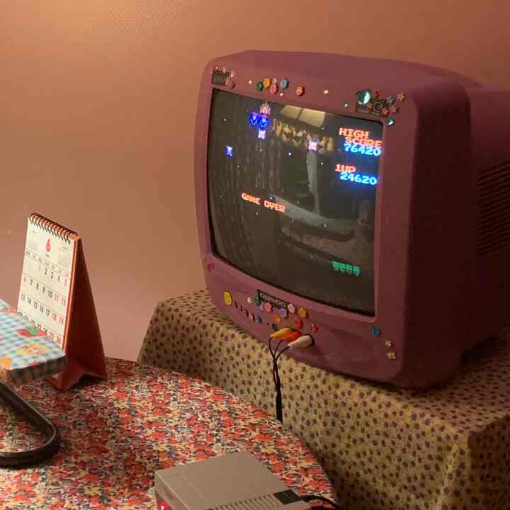 オレンジとベージュの色調が特徴のダイニングルーム、ヴィンテージテレビとレトロゲーム機が配置された雰囲気のある家族のゲームルーム