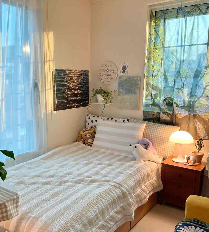 ベージュとホワイトの色調の落ち着いた寝室、シンプルな寝具とファブリックポスターが配置された印象的な空間