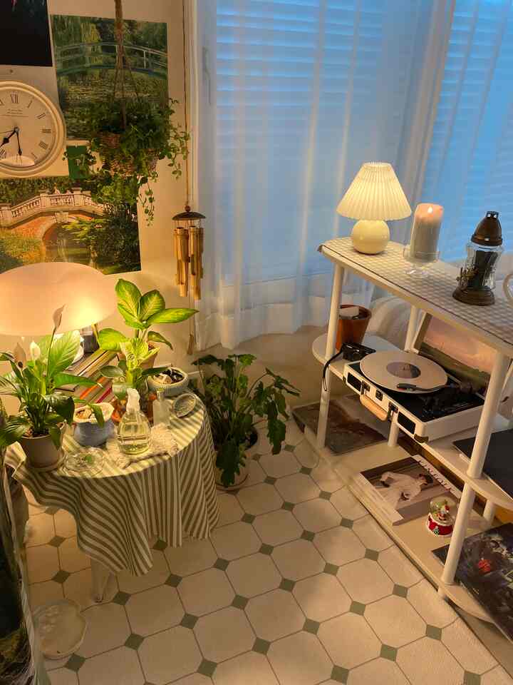 ナチュラルカラーと植物が調和した居心地の良いリビングルーム、ターンテーブルや照明、カーテンが配置され、落ち着いた雰囲気のインテリア。