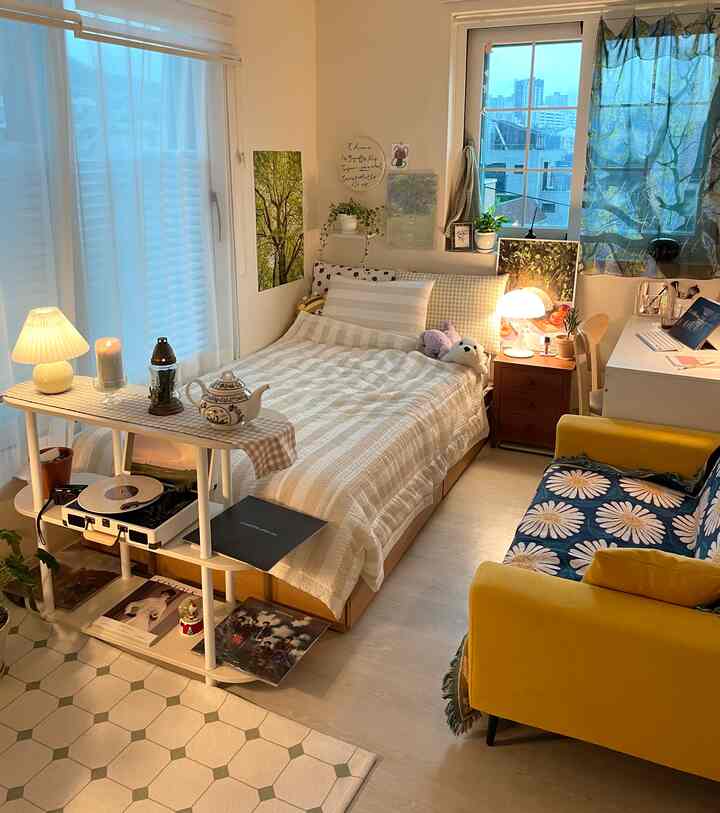 ホワイトとウッドトーンの調和があるワンルームの寝室、ベッドとデスク、黄色のソファが配置されたシンプルモダンなインテリア