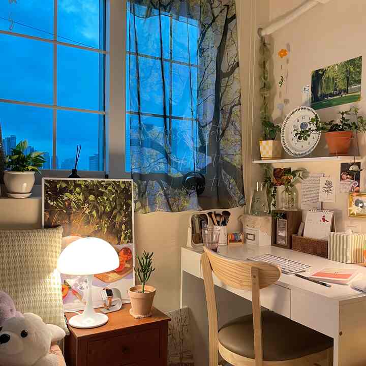 白と茶色のトーンのコンパクトなホームオフィス、デスクランプと植物が温かみのある雰囲気を演出