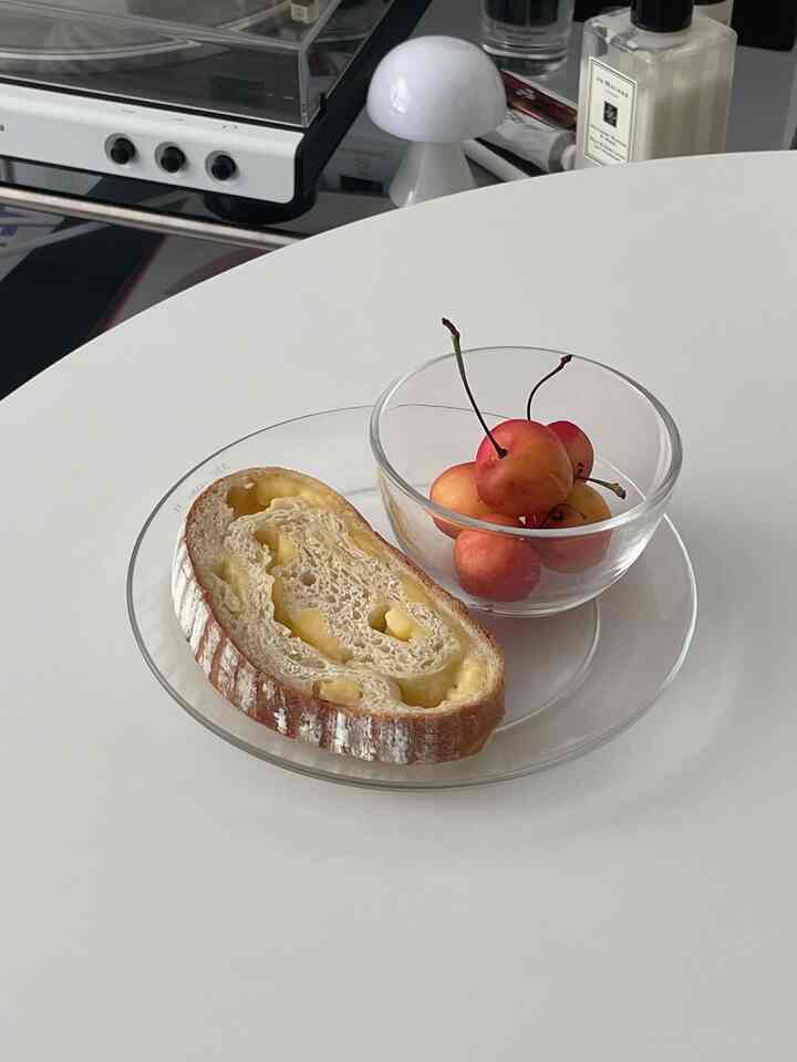 ホワイトトーンのダイニングテーブルにリスプレインのガラス皿とチェリーの入ったガラスボウルが置かれたシンプルなおうちカフェ