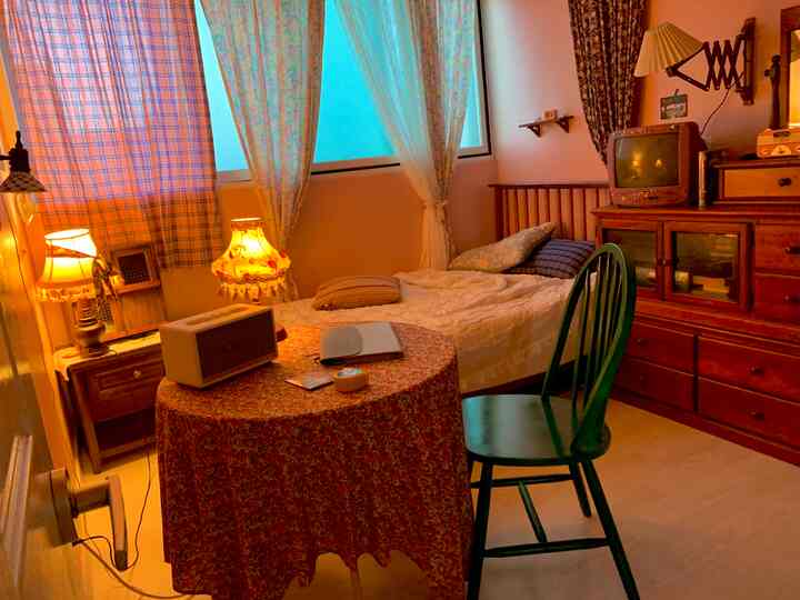 暖かいオレンジ色とブルーのトーンの寝室、木製ベッドとレトロな家具が配置された雰囲気のあるインテリア