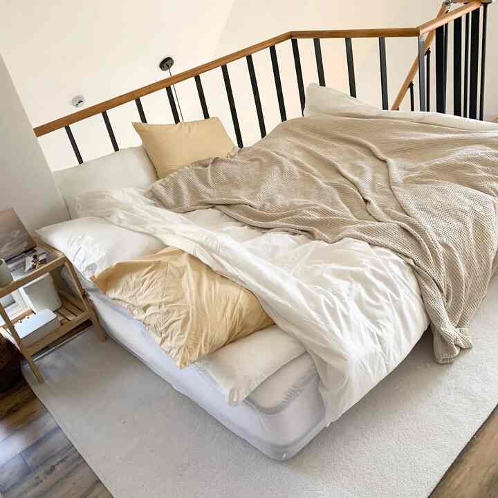 白と木目調が調和した寝室、枕と掛け布団が配置された雰囲気のあるインテリア