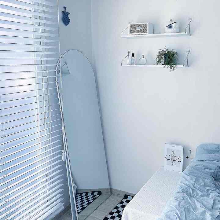 ホワイトとブルーのトーンの寝室、アーチ型ミラーと棚、すっきりとしたミニマルなインテリアが印象的な空間