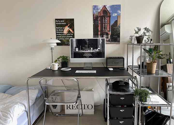 ブラックのデスクと透明な椅子が配置されたコンパクトなホームオフィス、ミッドセンチュリーモダンのシンプルなインテリア