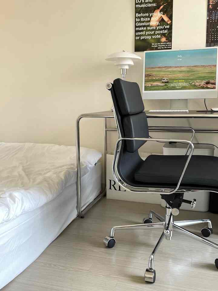 白を基調とした寝室兼ホームオフィス、シンプルで黒のオフィスチェアとパソコンが配置された落ち着いた空間