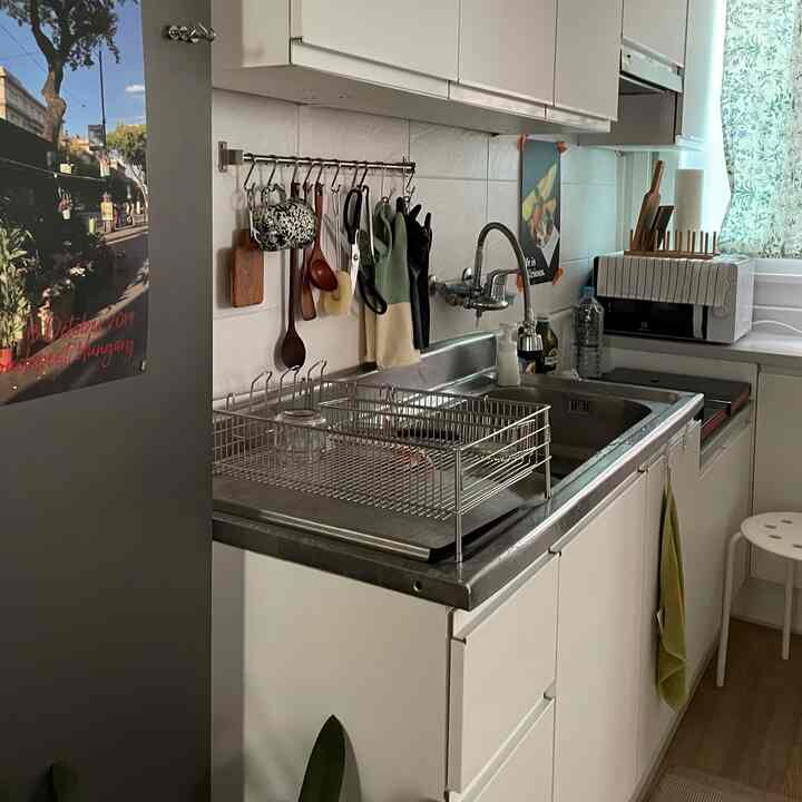 ホワイトと木目調の小さなキッチン、食器乾燥ラックと木製調理器具が整然と配置された実用的なインテリア