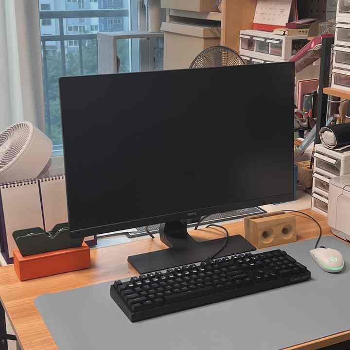 木目調とグレーのホームオフィス、モニターとキーボードのあるデスクと猫用キャットタワーが配置された実用的で居心地の良い作業空間