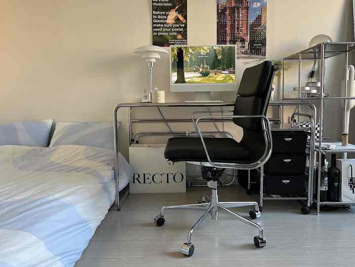 ホワイトとグレーのトーンでまとめられたミッドセンチュリーモダンな寝室兼ホームオフィス、ベッドとクローム製デスクが配置されたすっきりとした空間