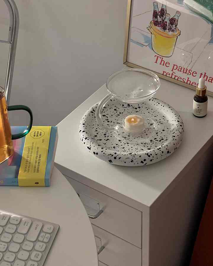 白を基調としたコンパクトな書斎空間、チェストの上にオイルバーナーとティーライトキャンドルが配置された整った雰囲気