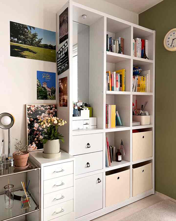 白とベージュのトーンの書斎空間、白い本棚とチェスト、植物と壁飾りで飾られた雰囲気のあるインテリア