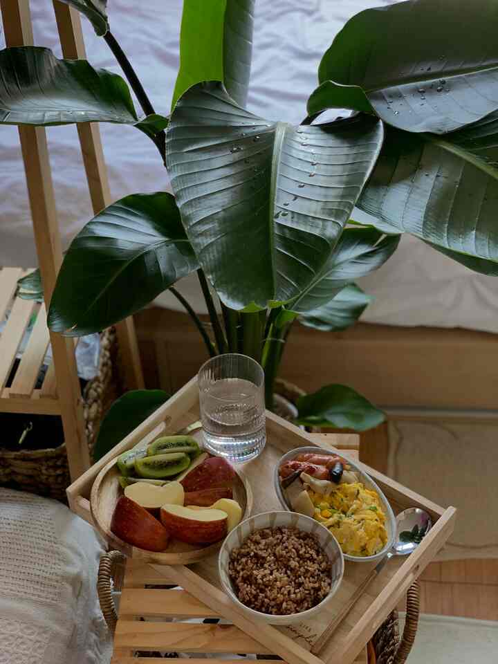 木目調と緑の植物が調和したリビング、竹製のトレイに朝食セットが置かれた雰囲気ある空間