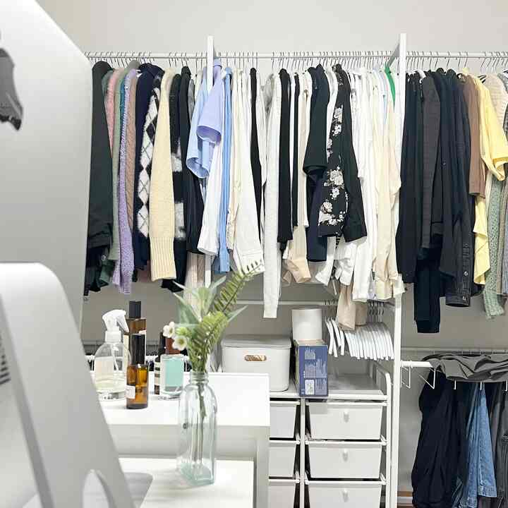 白を基調とした寝室の収納スペース、中央に長いハンガーラックとチェストが配置された整理された収納エリア