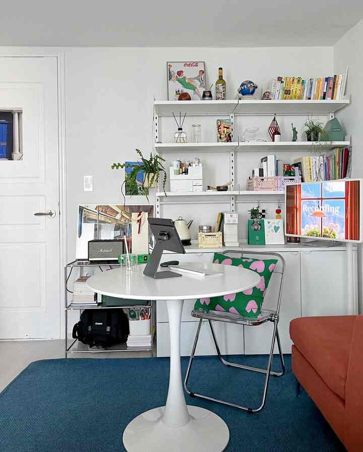 白と青のトーンのホームオフィス、丸いテーブルと本棚が配置された清潔感のあるモダンなワークスペース