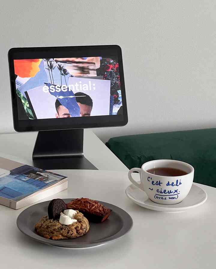 白とグレーのトーンのモダンなおうちカフェ空間、テーブル上にティーカップ、皿、タブレットと本が配置された雰囲気のあるインテリア