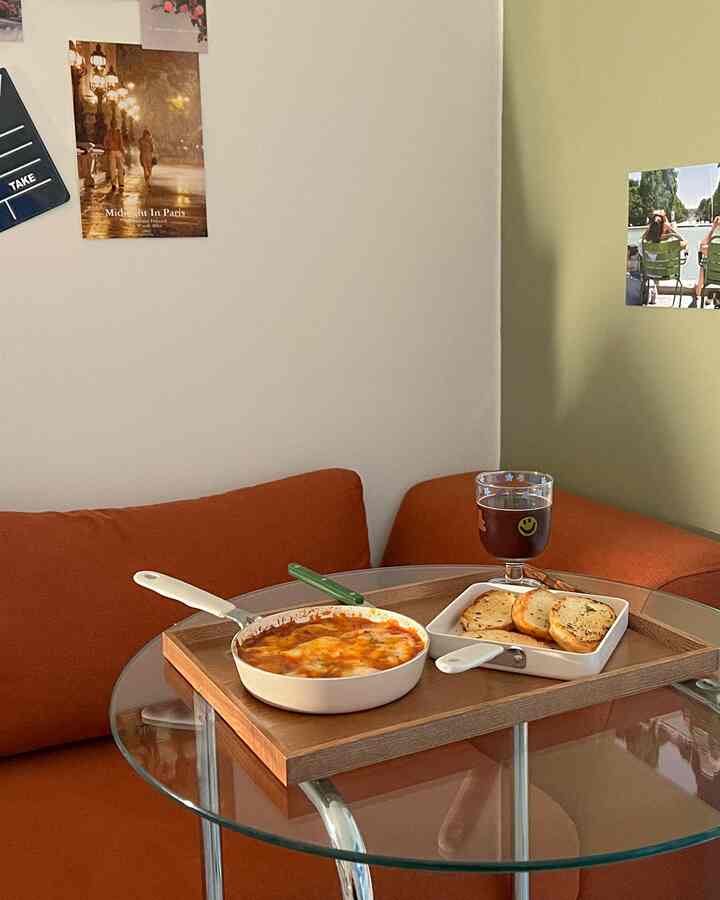 オレンジのソファと透明なガラステーブルが配置された、抜け感のあるミニマルな狭い部屋