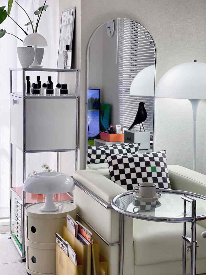 ホワイトトーンのワンルームリビング、ルイスポールセンのパンテラフロアランプとル・コルビュジエのLC2アームチェア、アーチ型の全身鏡が配置されたモダンなインテリア