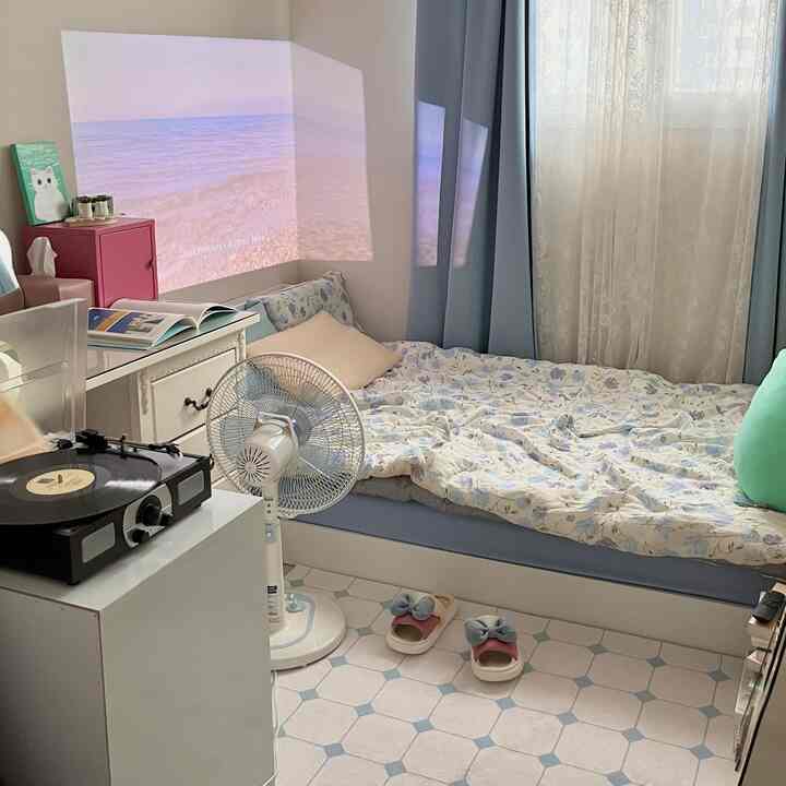 パステルカラーと白と青を基調とした寝室、ベッドとレトロなレコードプレーヤーが置かれた雰囲気のあるインテリア