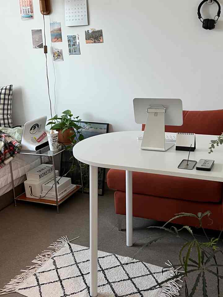 暖かいナチュラルカラーのリビング、オレンジのソファと白いデスク、サイドテーブルが配置された雰囲気のあるインテリア