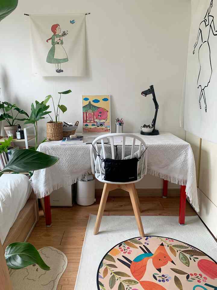 白と赤が調和したワンルームのコンパクトなホームオフィス、植物とポスターで明るくシンプルな雰囲気のインテリア