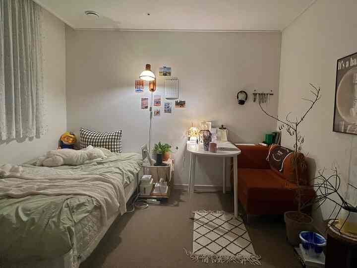 暖かい照明とオレンジのソファ、ベッド、植物が配置されたモダンで居心地の良い小さな寝室のインテリア