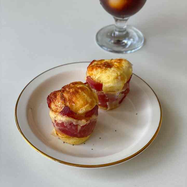 ゴールドの縁取りがある白い皿に置かれた卵パンと飲み物があるシンプルなホームカフェのブランチシーン