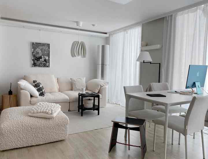 ホワイトとベージュのトーンのリビング、ソファとダイニングチェア、コンピューターが配置されたシンプルモダンな雰囲気のあるインテリア