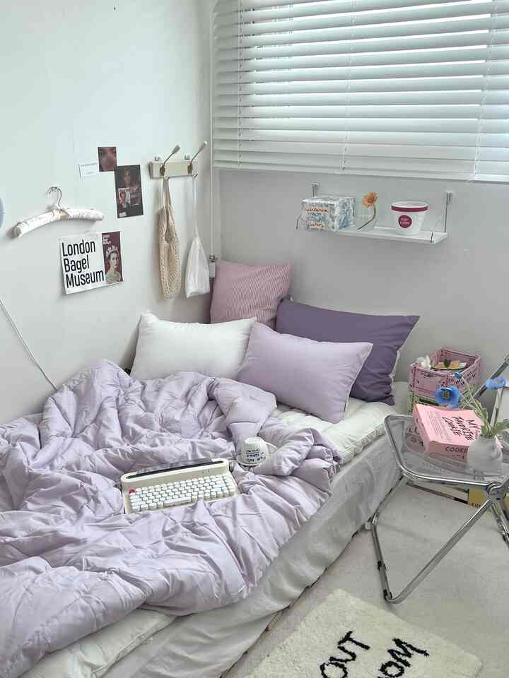 ホワイトとラベンダーカラーの寝室、クッションと寝具が調和したモダンで落ち着いたインテリア